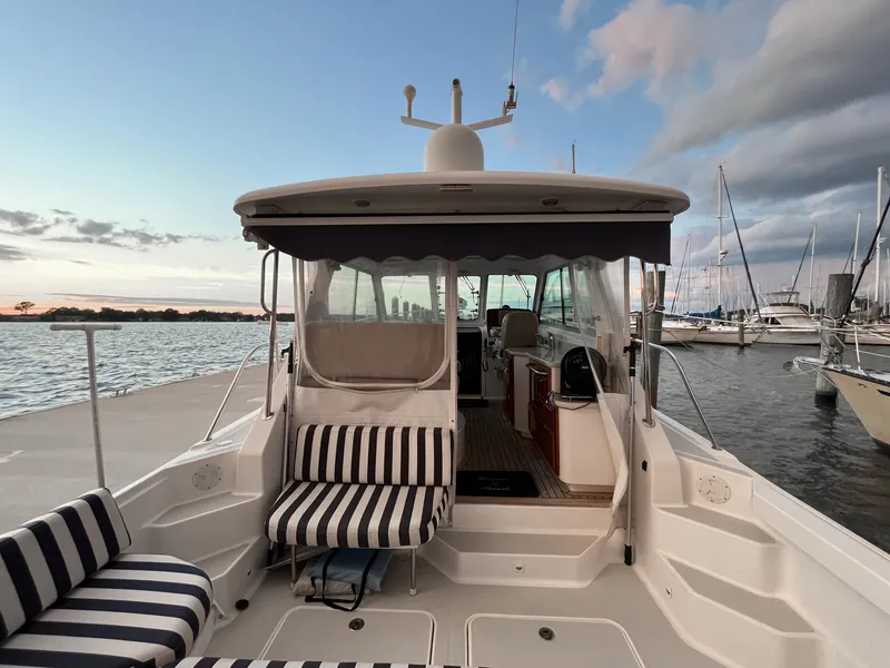 Slide: The Image of 2013 Back Cove 34 boat docked, featuring striped seating and a scenic waterfront view. - 35