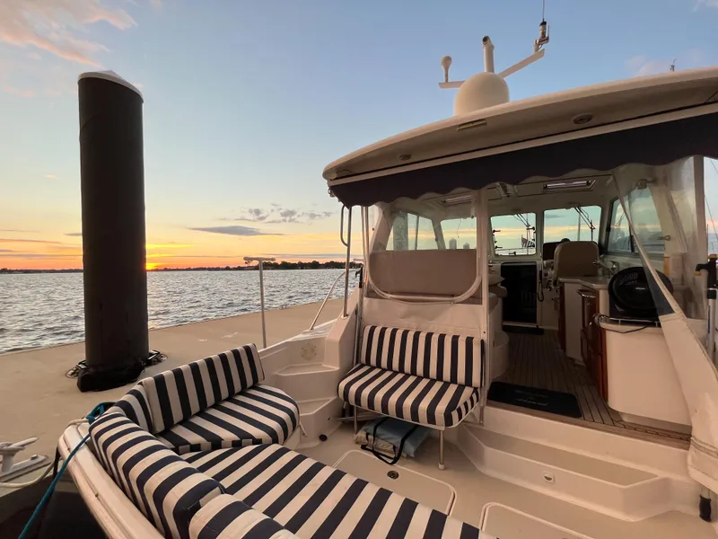 Slide: The Image of 2013 Back Cove 34 yacht with striped seating at sunset by the water. - 37