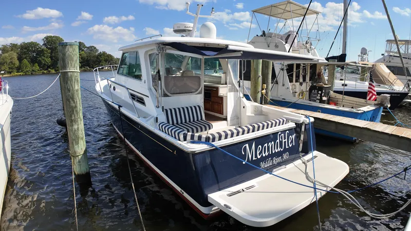 Slide: The Image of 2013 Back Cove 34 boat docked, featuring striped seating and "MeandHer" name on the stern. - 8