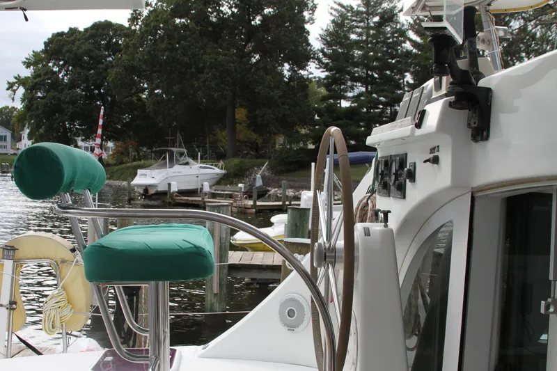 Slide: The Image of Lagoon 380 catamaran helm with green seats, docked by a scenic waterfront. - 17