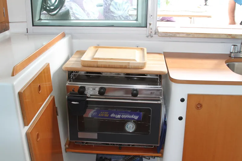 Slide: The Image of Compact kitchen area in a 2004 Lagoon 380 catamaran with stove and wooden cabinetry. - 19