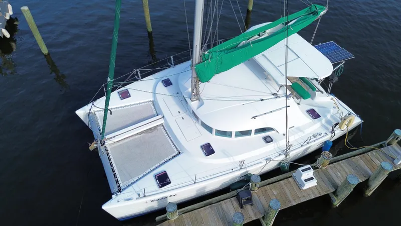 Slide: The Image of Aerial view of 2004 Lagoon 380 catamaran docked, featuring green sail and solar panel. - 2