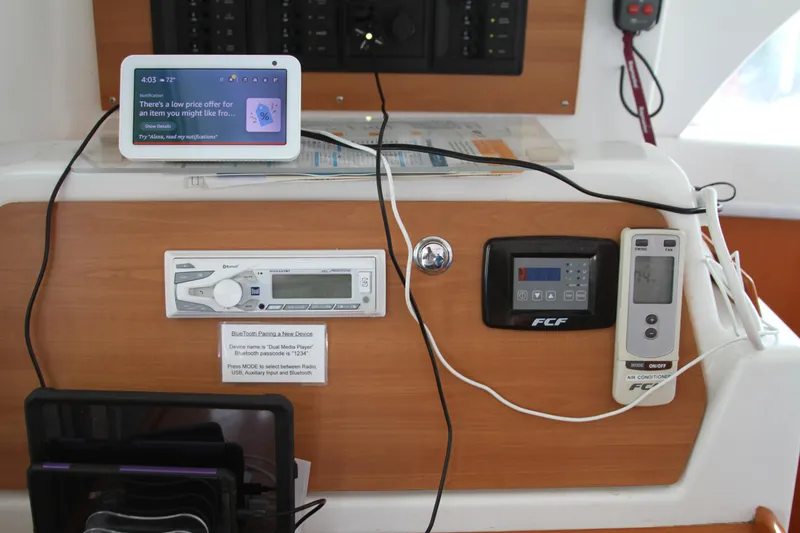 Slide: The Image of Control panel of a 2004 Lagoon LAGOON 380 catamaran with electronic devices and air conditioner remote. - 26
