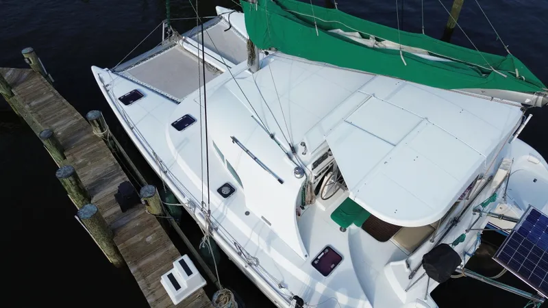 Slide: The Image of 2004 Lagoon LAGOON 380 catamaran docked, featuring green sail cover and solar panel. - 3