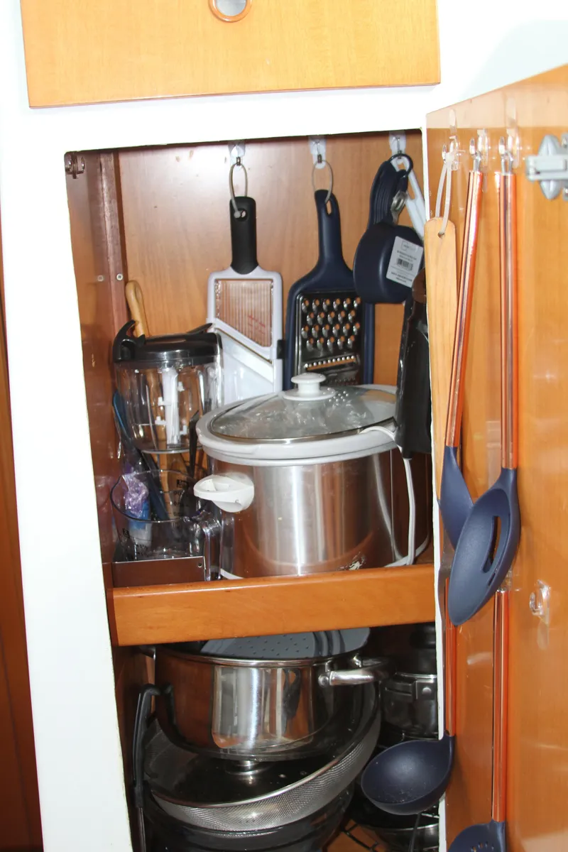 Slide: The Image of Kitchen storage in 2004 Lagoon 380 yacht, featuring cookware and utensils. - 32