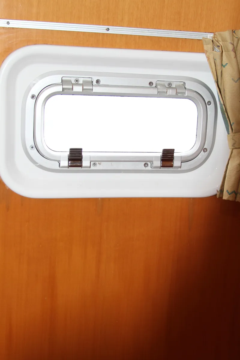 Slide: The Image of Porthole window inside 2004 Lagoon LAGOON 380 catamaran with wooden interior. - 38