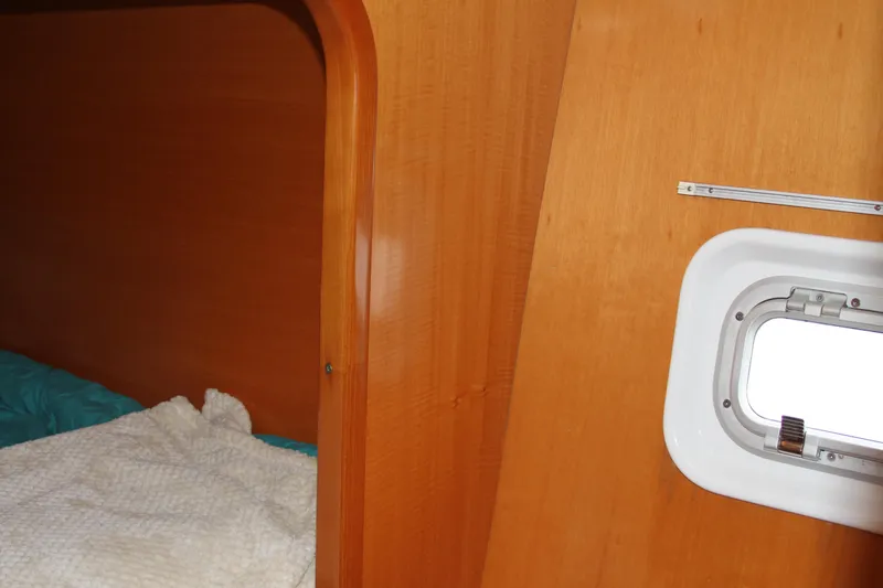 Slide: The Image of Interior cabin of 2004 Lagoon 380 catamaran with wooden paneling and a small window. - 39