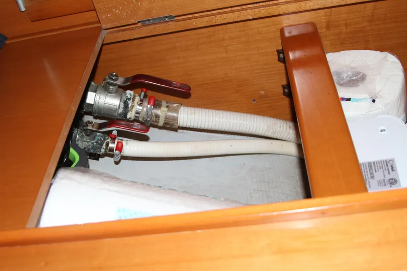 Slide: The Image of Wooden cabinet interior with plumbing pipes and valves on a 2004 Lagoon 380 boat. - 41