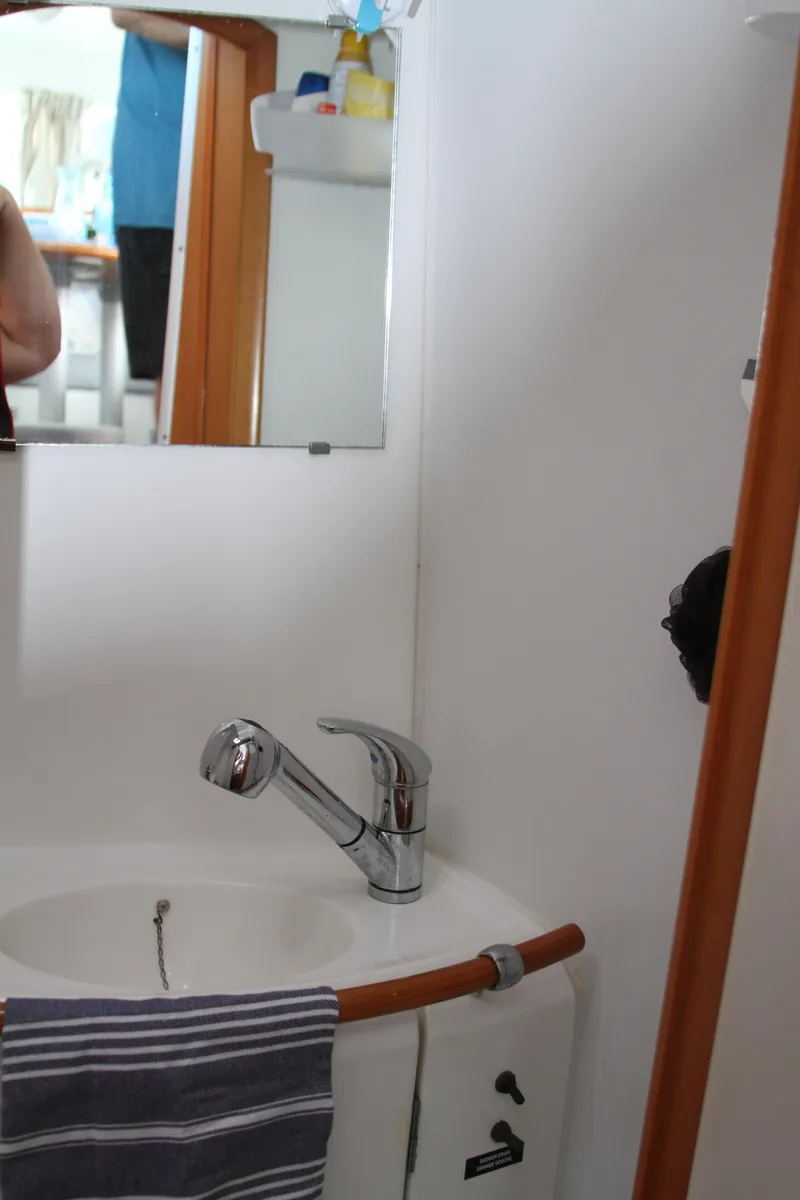 Slide: The Image of Bathroom sink area in 2004 Lagoon 380 catamaran, featuring a mirror and faucet. - 42