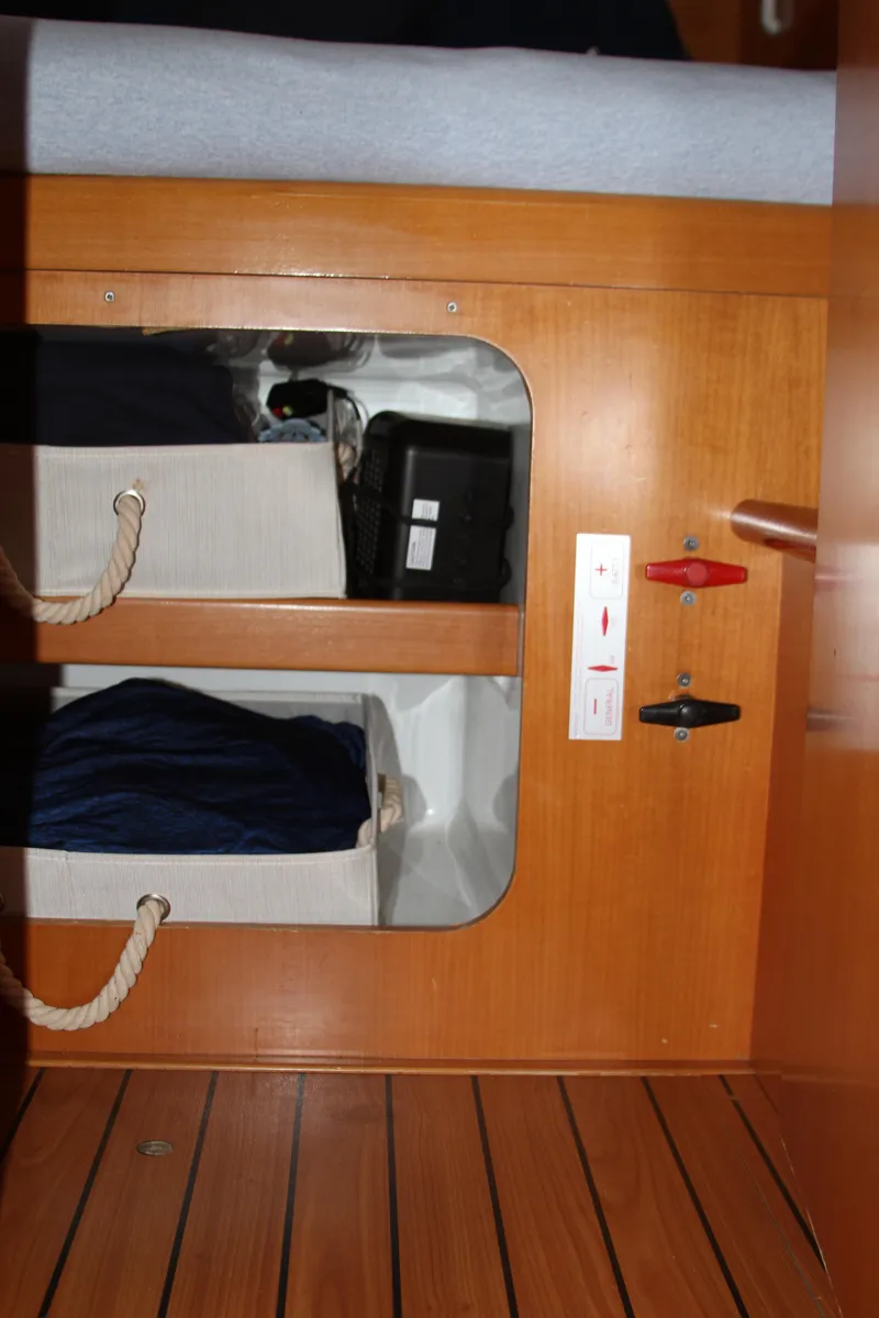 Slide: The Image of Interior storage compartment on 2004 Lagoon 380 catamaran with wooden finish and rope handles. - 45