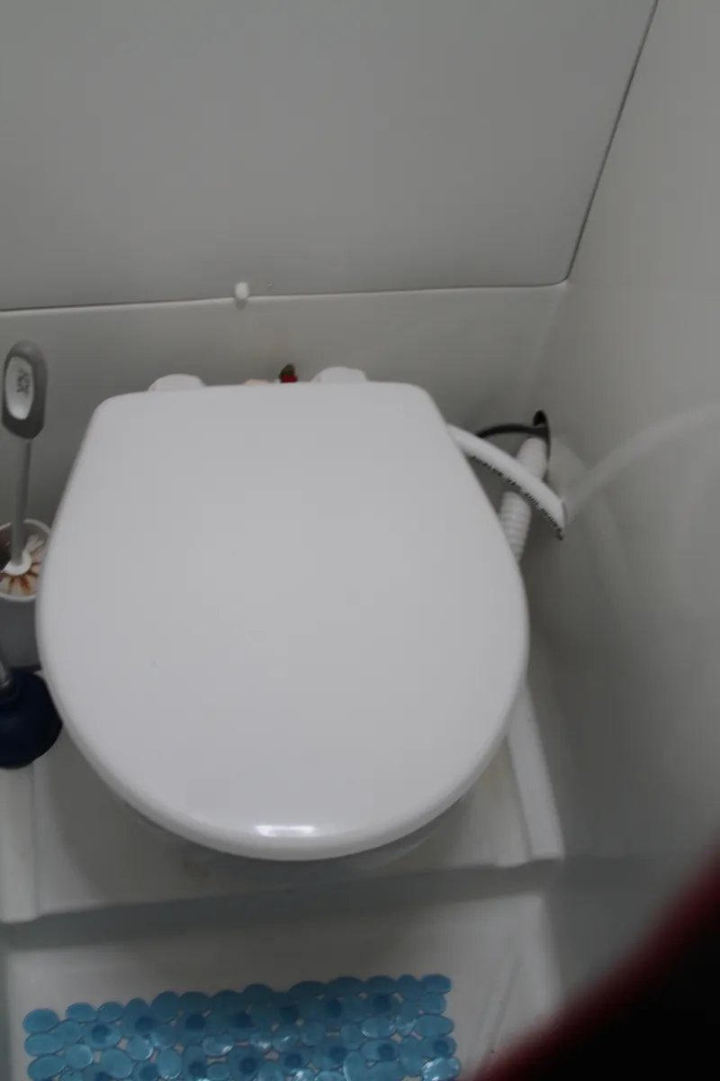 Slide: The Image of Toilet in 2004 Lagoon 380 yacht bathroom with white seat and blue mat. - 49