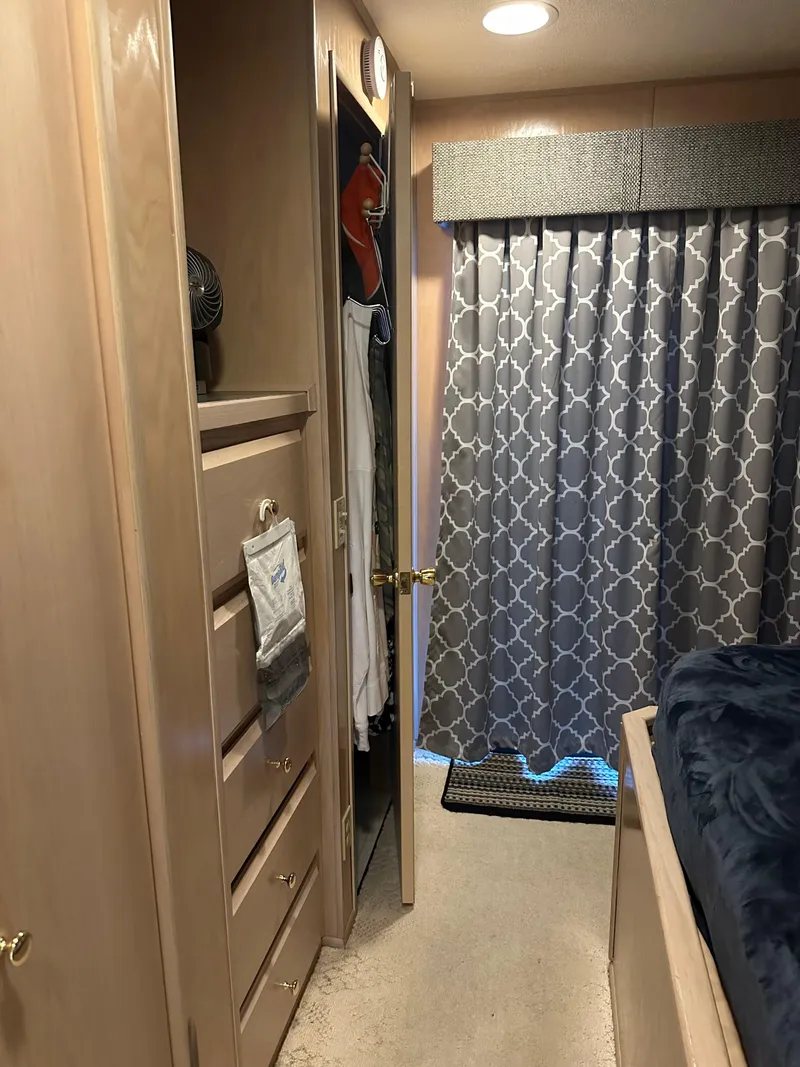 Slide: The Image of Interior of a 1999 Lakeview houseboat with closet, drawers, and patterned curtains. - 13