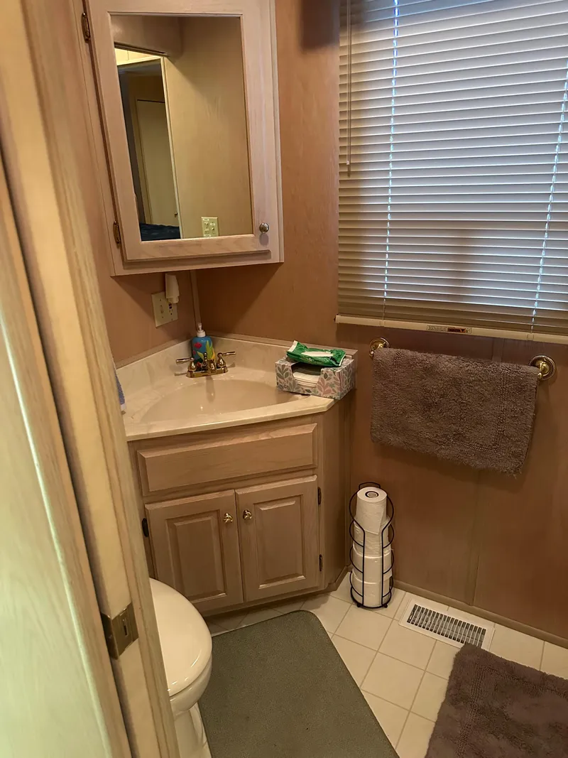 Slide: The Image of Bathroom interior of a 1999 Lakeview houseboat with wooden cabinets and blinds. - 17