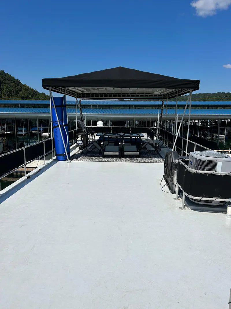 Slide: The Image of 1999 Lakeview Houseboat with canopy on deck, docked under clear blue sky. - 18