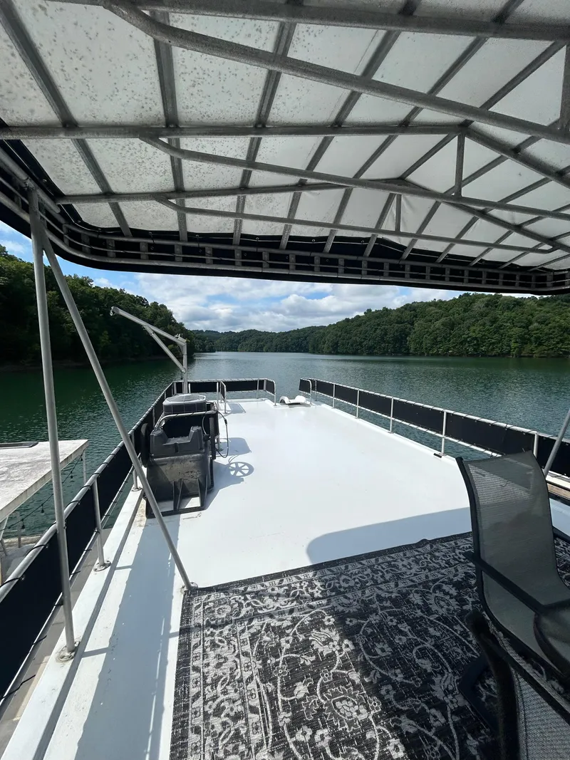Slide: The Image of 1999 Lakeview houseboat deck with seating, overlooking serene lake and lush greenery. - 19