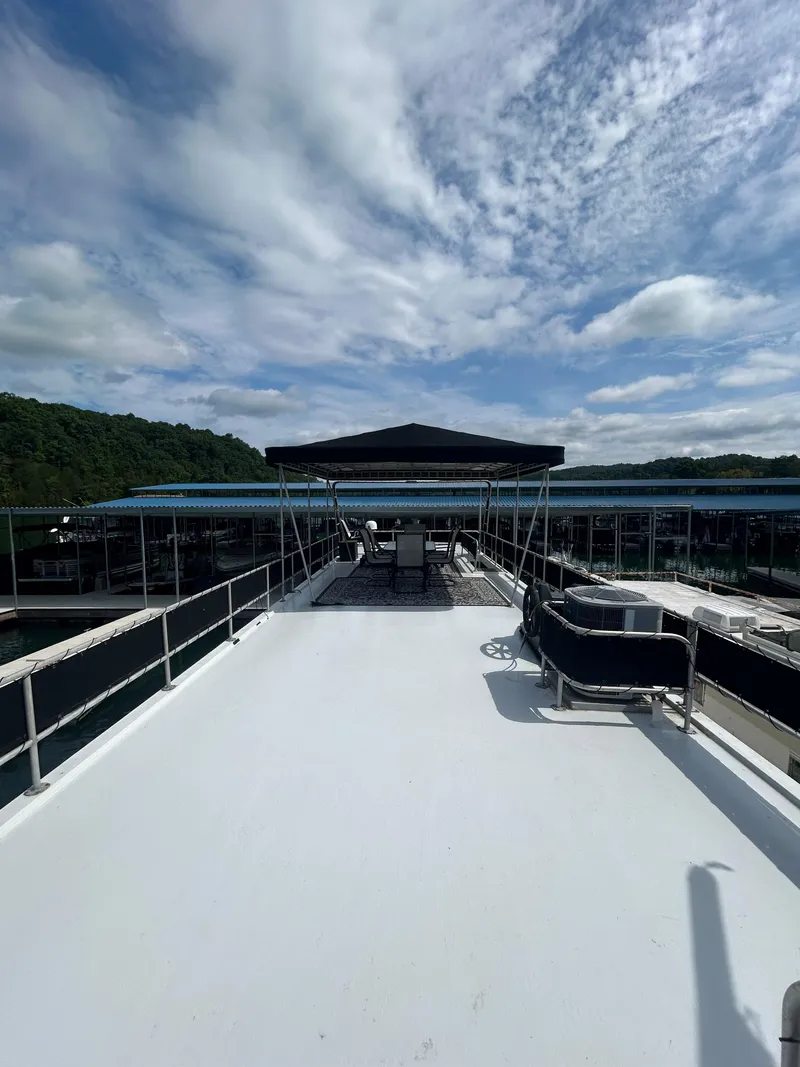 Slide: The Image of 1999 Lakeview Houseboat with spacious deck under a partly cloudy sky. - 20