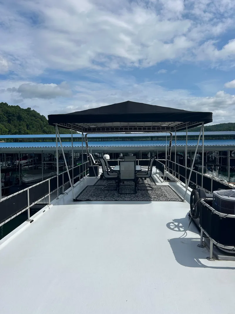 Slide: The Image of 1999 Lakeview houseboat with shaded deck, outdoor seating, and scenic marina view. - 21