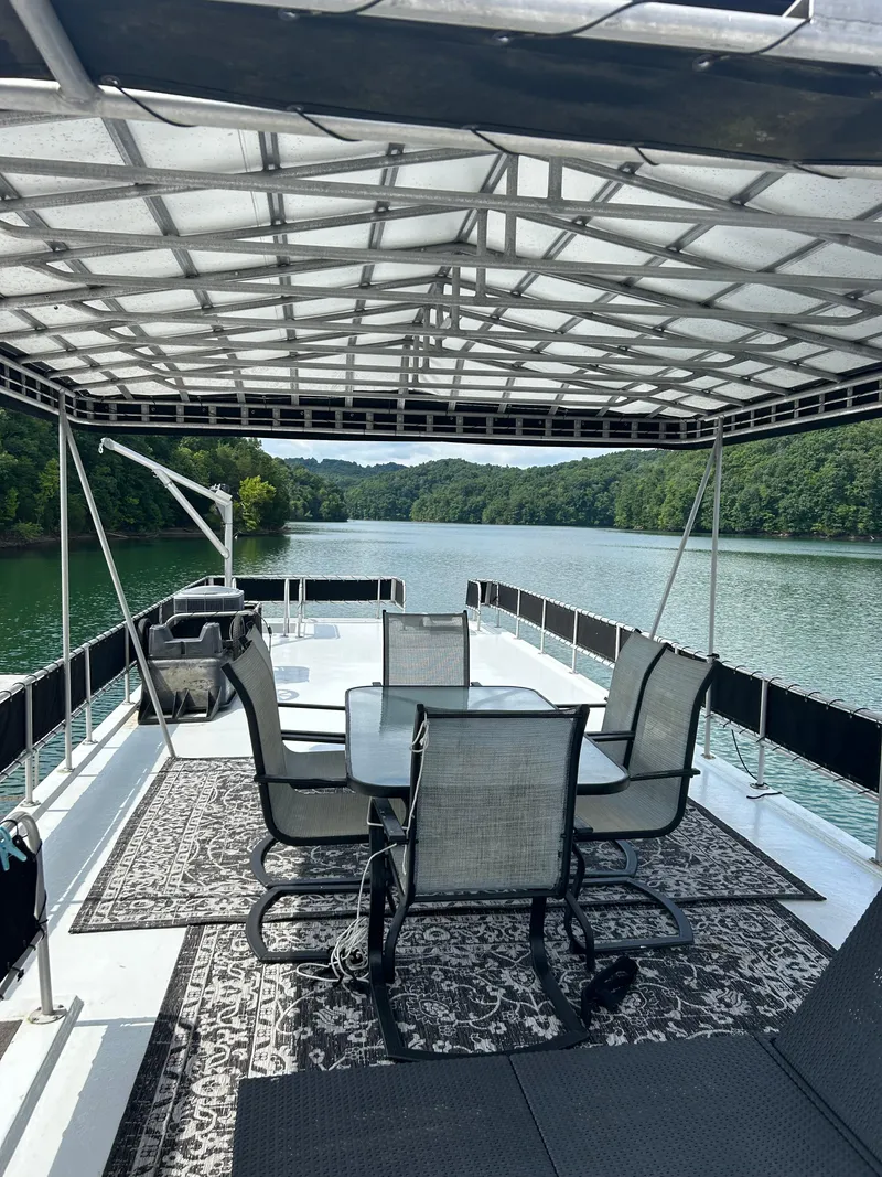 Slide: The Image of 1999 Lakeview houseboat with outdoor seating on a serene lake. - 23