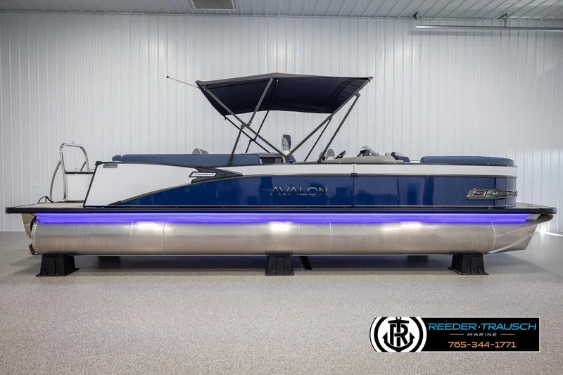 Slide: The Image of 2025 Avalon Catalina Entertainer pontoon boat with blue accents and canopy in showroom. - 5