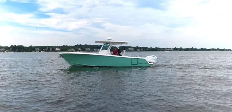 Slide: The Image of A green motorboat cruising on calm water, with two people on board. - 32