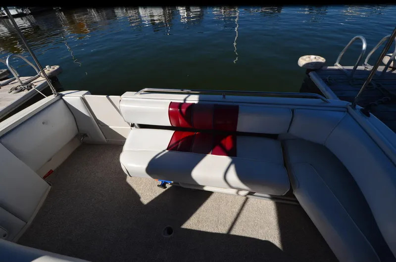 Slide: The Image of 1992 Sea Ray 290 Sundancer boat interior with white seating and red cushion by the water. - 19