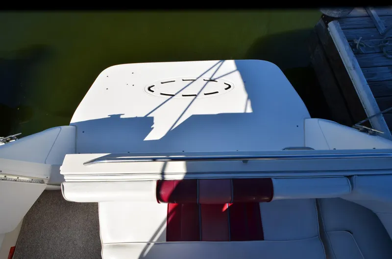 Slide: The Image of 1992 Sea Ray 290 Sundancer boat deck with red seating, docked by the water. - 21