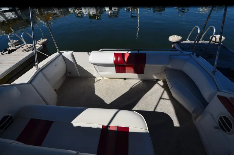 Slide: The Image of 1992 Sea Ray 290 Sundancer boat interior with red and white seating, docked by the water. - 25
