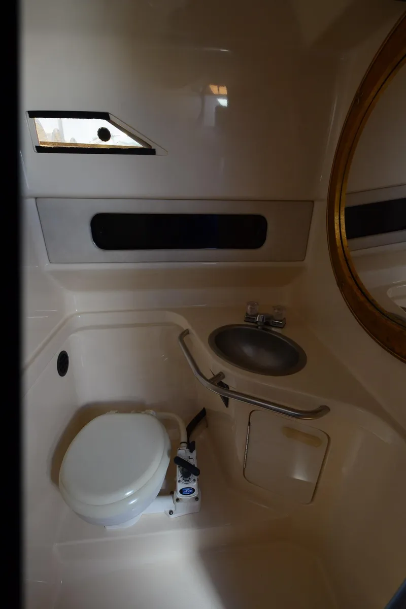 Slide: The Image of 1992 Sea Ray 290 Sundancer bathroom with toilet, sink, and porthole window. - 31
