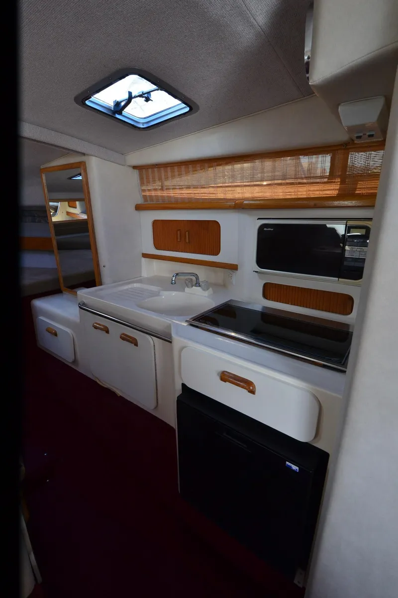 Slide: The Image of 1992 Sea Ray 290 Sundancer interior kitchen with sink, stove, and storage cabinets. - 32