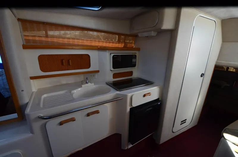 Slide: The Image of 1992 Sea Ray 290 Sundancer boat kitchen with sink, stove, and microwave. - 9