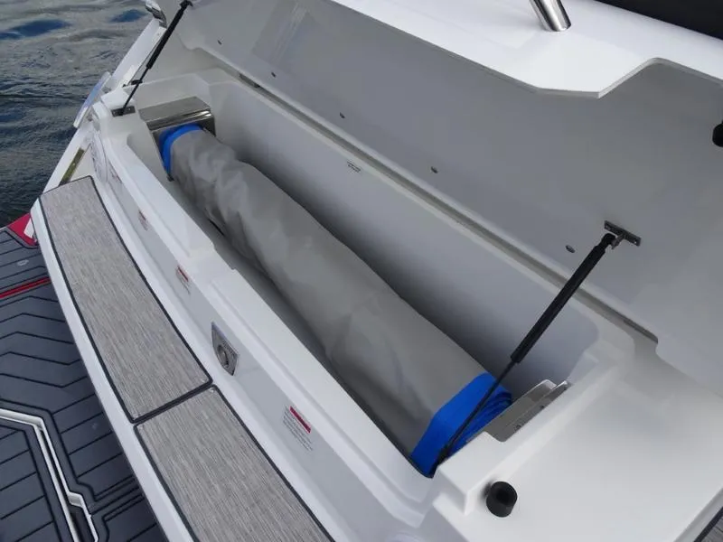 Slide: The Image of Cobalt R33 2025 boat storage compartment with gray cover and hydraulic supports. - 11
