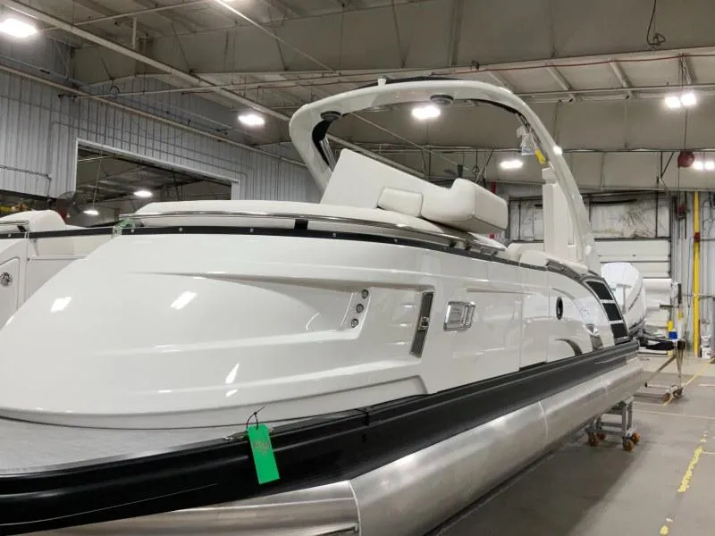 The Image of 2024 Bennington 27QXSBA-T2 pontoon boat in a showroom, sleek white design. - 0