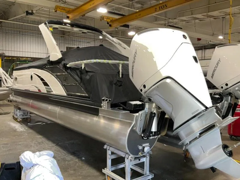 Slide: The Image of 2024 Bennington 27QXSBA-T2 pontoon boat with Mercury outboard in a warehouse. - 2