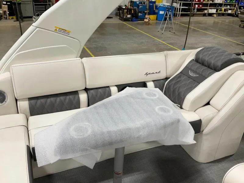 Slide: The Image of 2024 Bennington 27QXSBA-T2 boat interior with luxury seating and table in a workshop. - 6