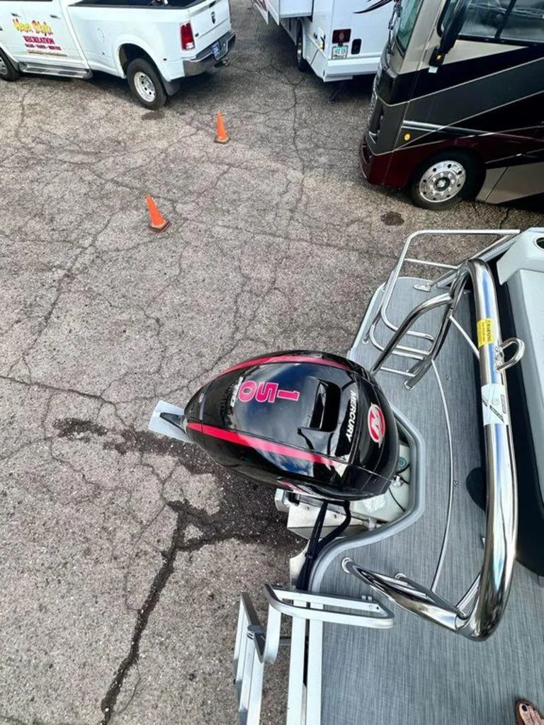 Slide: The Image of 2024 Lowe SS21CL boat with outboard motor, parked near vehicles on a paved surface. - 9