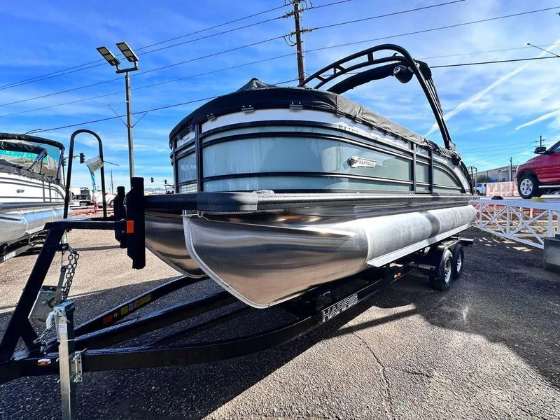 Slide: The Image of 2024 Harris Solstice 230 pontoon boat on trailer, displayed outdoors under clear blue sky. - 2
