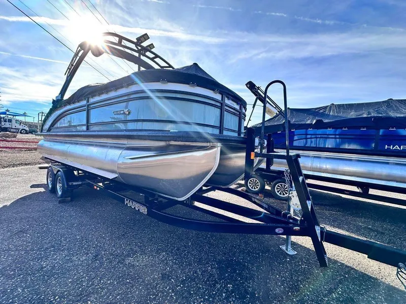 Slide: The Image of 2024 Harris Solstice 230 pontoon boat on trailer under bright sun. - 3