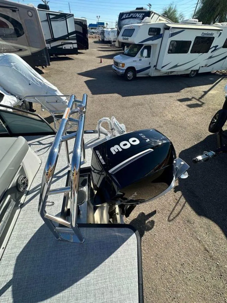 Slide: The Image of 2024 Harris Solstice 230 boat with powerful outboard motor, parked near RVs. - 7