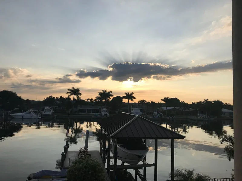 Slide: The Image of Sunset over marina with 2017 Regal 29 OBX boat docked, palm trees silhouetted. - 7