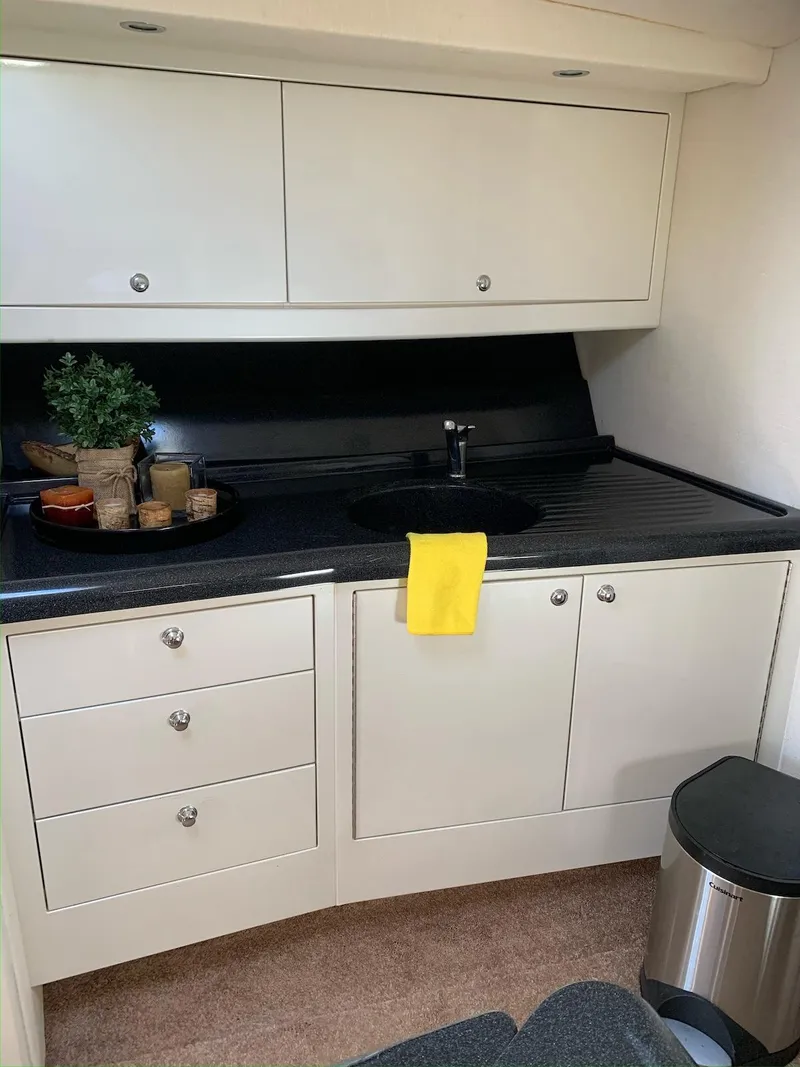 Slide: The Image of 1996 Wellcraft 45 Excalibur yacht kitchen with white cabinets and black countertop. - 14