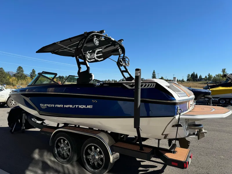 Slide: The Image of 2017 Nautique GS20 boat on trailer, blue and white, with wakeboard tower, parked outdoors. - 5