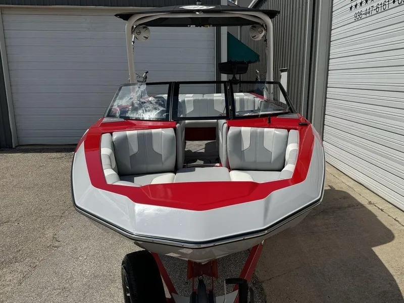 Slide: The Image of 2022 Malibu 21 LX boat with red and white design, parked outside a garage. - 17