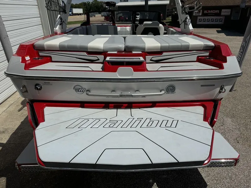 Slide: The Image of 2022 Malibu 21 LX boat, rear view with red and white seating and swim platform. - 5