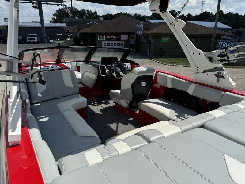 Slide: The Image of 2022 Malibu 21 LX boat interior with red and gray seating, steering wheel, and dashboard. - 8
