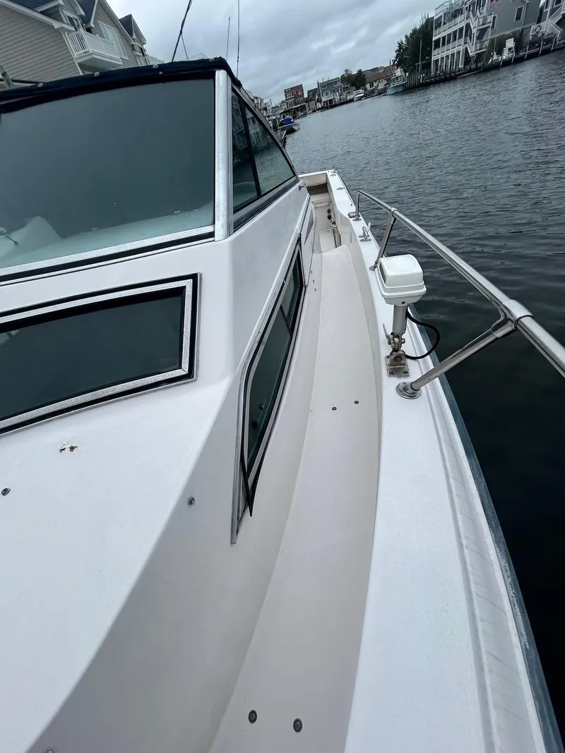 Slide: The Image of 1993 Grady-White 24 Explorer boat on a calm waterfront, showcasing sleek design and spacious deck. - 22