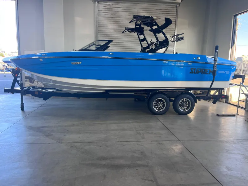 Slide: The Image of 2025 Supreme S240 boat in showroom, blue and white design on trailer. - 1