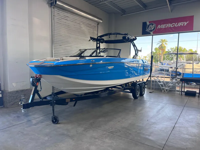 Slide: The Image of 2025 Supreme S240 boat in showroom, blue and white design, on trailer. - 2