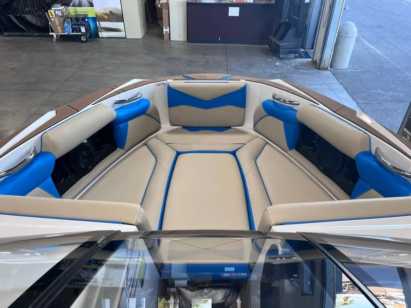 Slide: The Image of 2025 Supreme S240 boat interior with beige and blue seating in a showroom. - 8