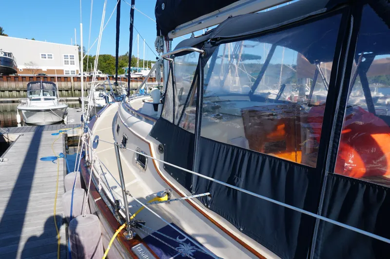 Slide: The Image of 1994 Island Packet 32 sailboat docked at marina, featuring protective covers and visible rigging. - 10
