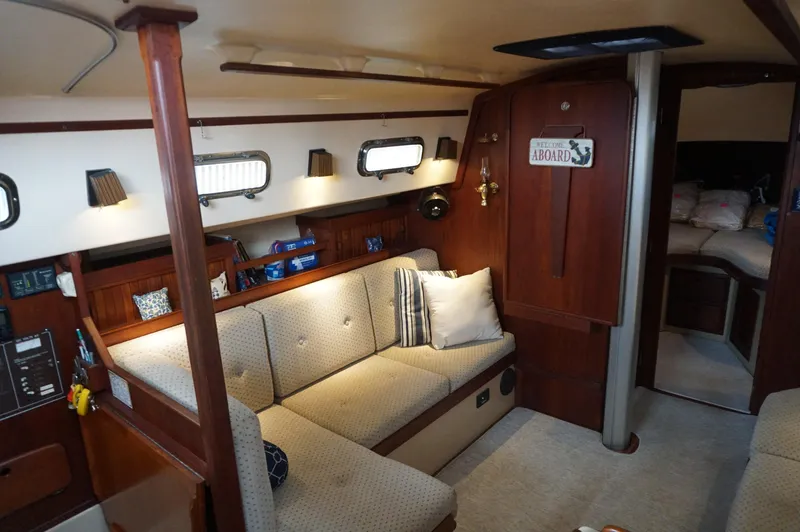 Slide: The Image of Cozy interior of a 1994 Island Packet 32 sailboat with cushioned seating and wooden accents. - 15